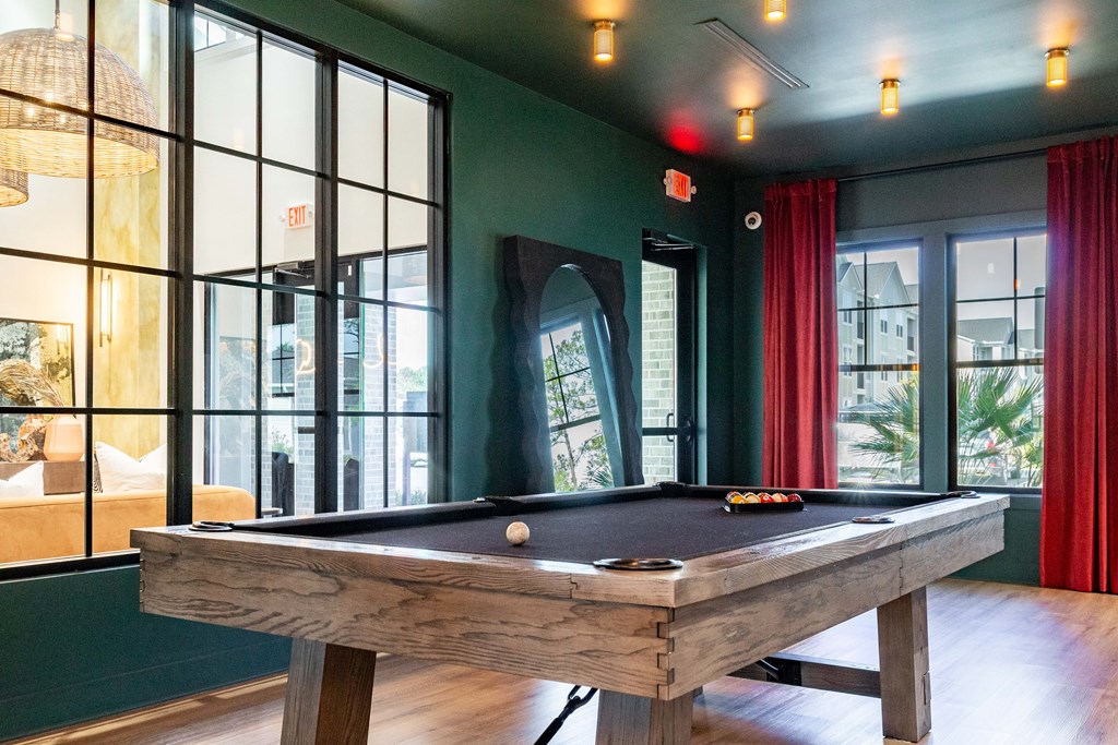 A pool table in a room with a view of the city at Evolve Waterford Apartments in Belville, NC.