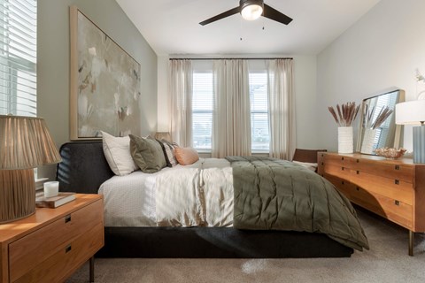 A bedroom with a bed, nightstand, and a painting on the wall.