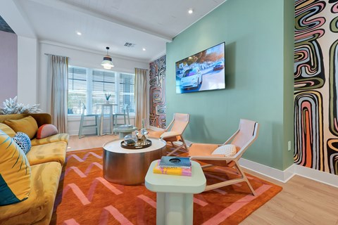 A living room with a yellow couch and a television on the wall.
