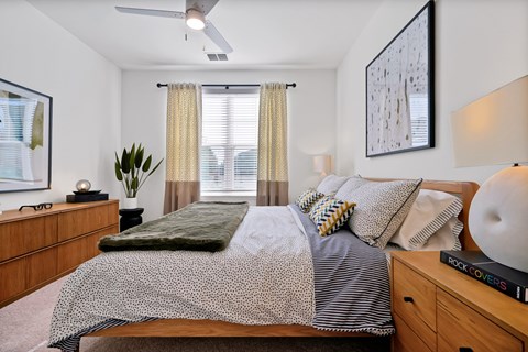 A bedroom with a bed, nightstand, and a painting on the wall.