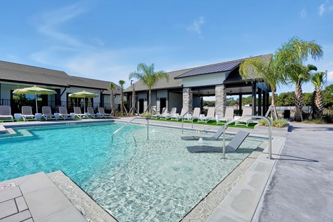A large swimming pool with a glass barrier and a building in the background.