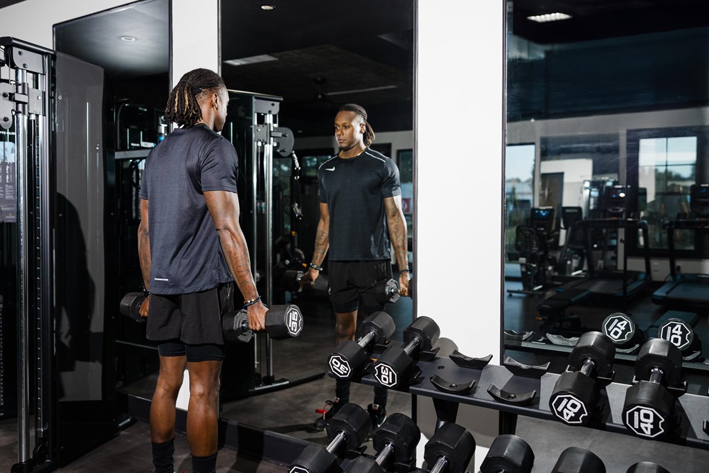 A man in a gym is working out with dumbbells.