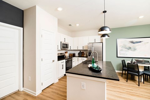 A kitchen with white cabinets and a black countertop.