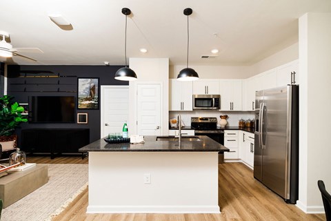 A modern kitchen with a black countertop and stainless steel appliances.