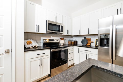 A kitchen with white cabinets and a black countertop.
