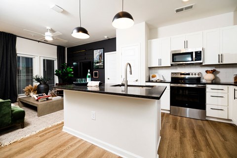 A modern kitchen with white cabinets and a black countertop.