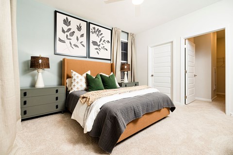 A bedroom with a bed, nightstand, and two framed pictures on the wall.