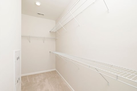A white walk in closet with shelves and a door.