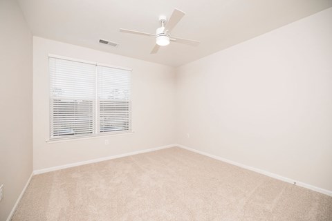 A room with a ceiling fan and a window with blinds.