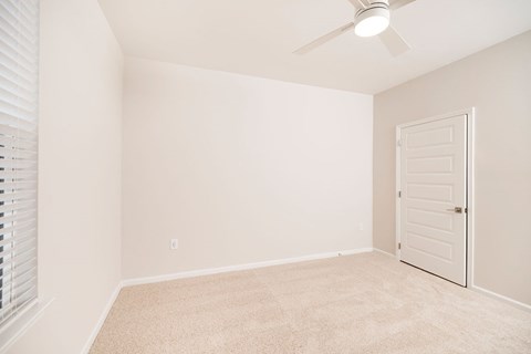 A room with a white door and a ceiling fan.