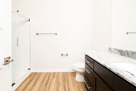 A bathroom with a toilet, sink, and a glass shower door.