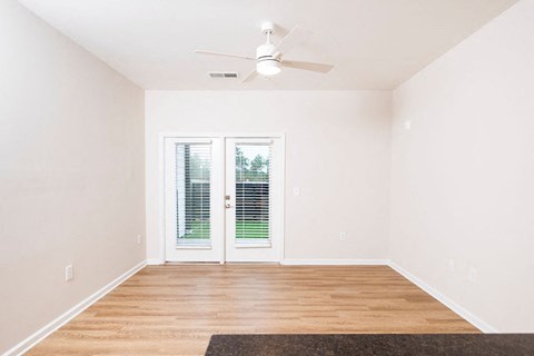 A room with a ceiling fan and sliding glass doors.