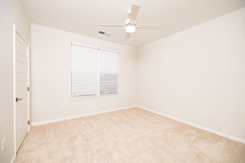 A room with a ceiling fan and a window with blinds.