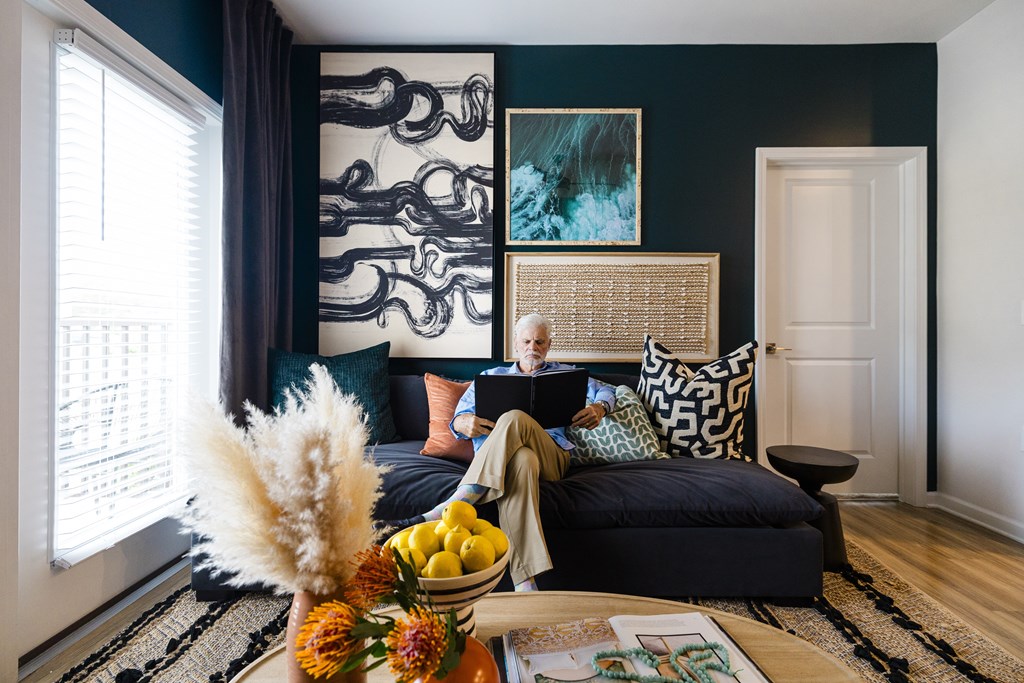 A woman is sitting on a black couch with a laptop on her lap.