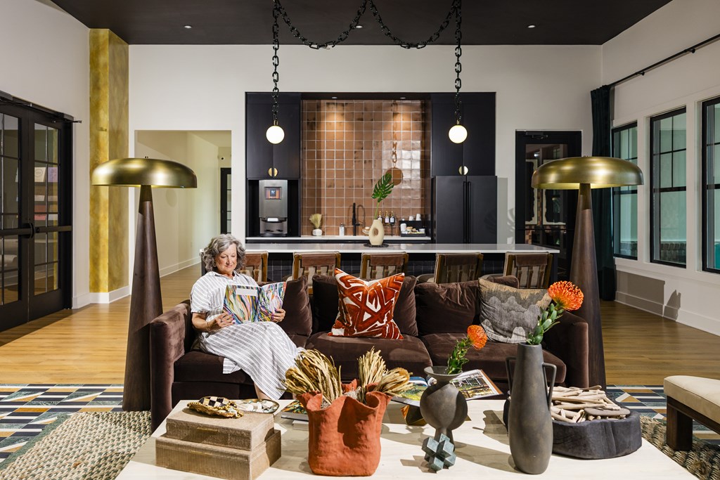 A woman is sitting on a couch in a living room with a coffee table in front of her.