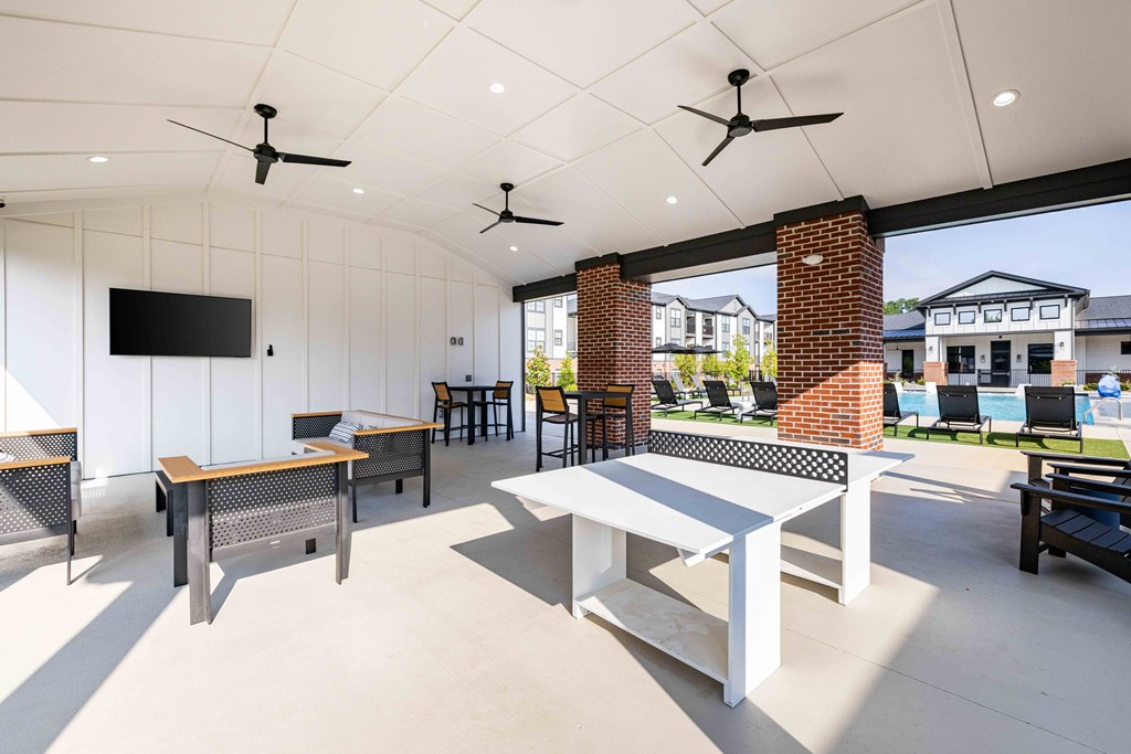 A patio with a white table and chairs and a brick pillar.