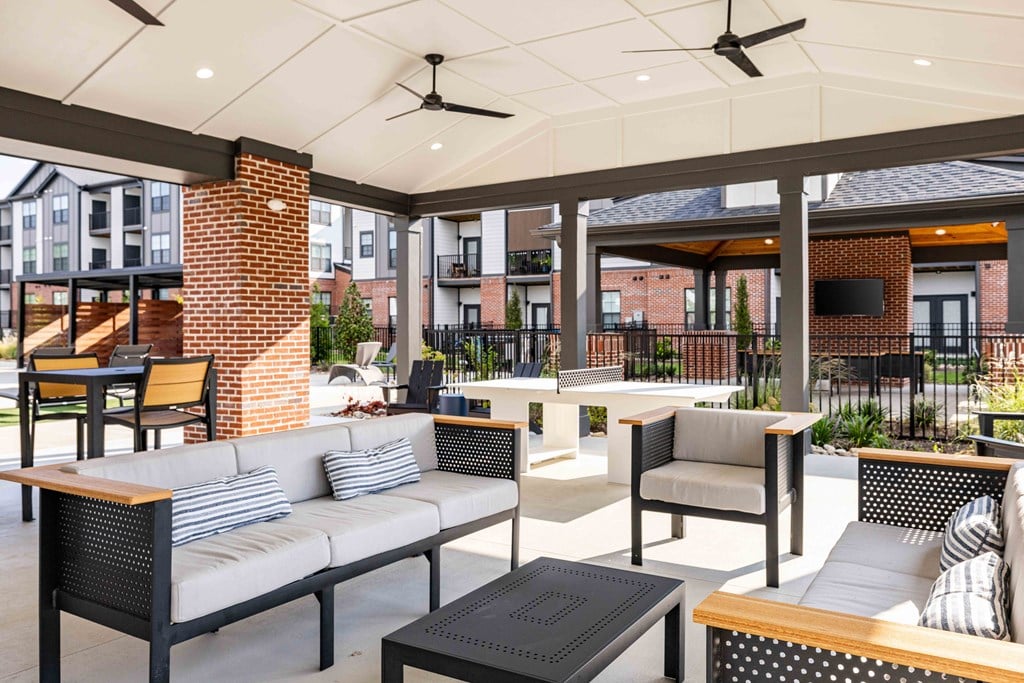 A patio with a brick pillar and a ceiling fan.