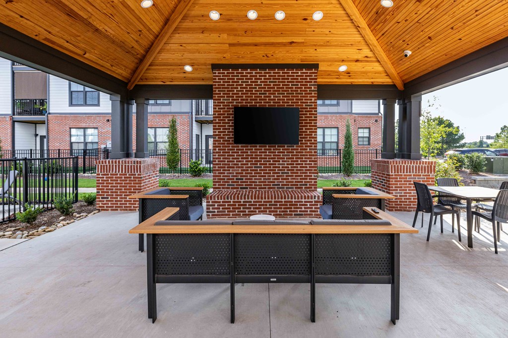 A black table with a television on a brick wall in a covered patio.