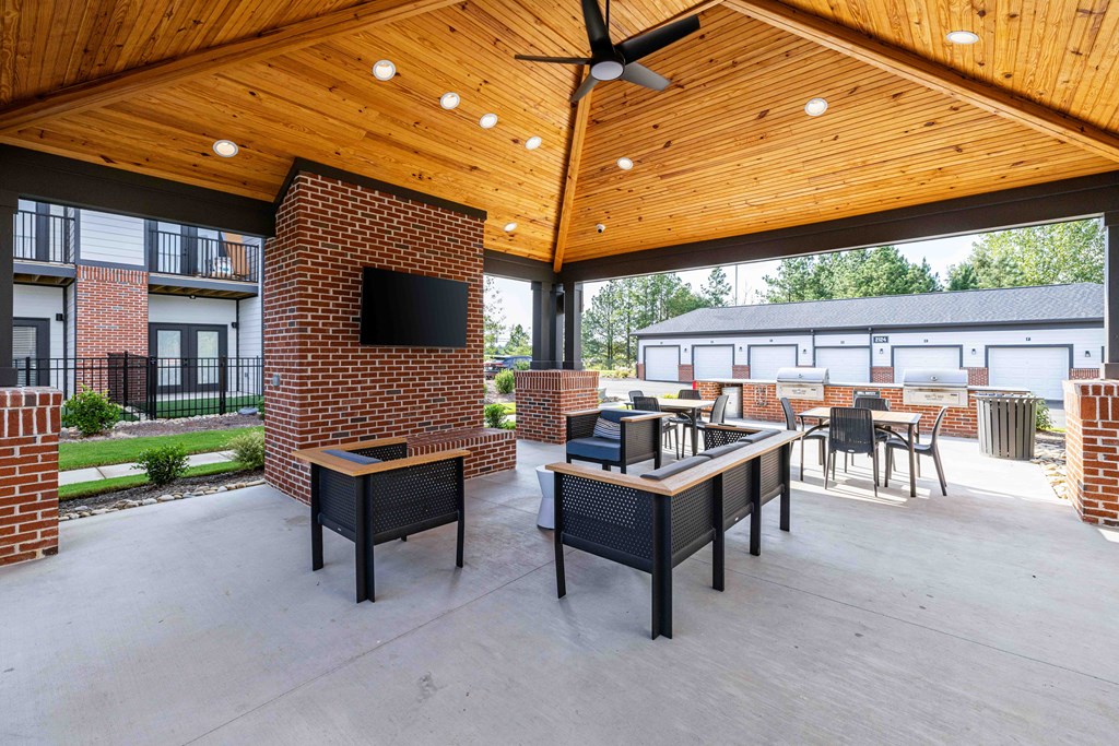 A patio with a table and chairs and a television on a brick wall.
