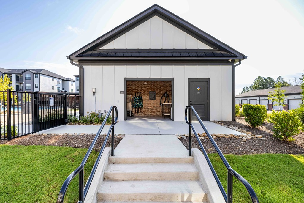 A small white building with a black roof and a black gate in front.
