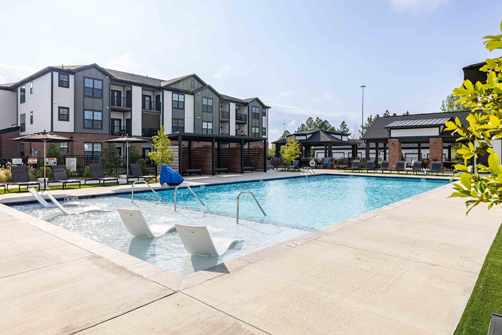 A swimming pool with lounge chairs and a building in the background.