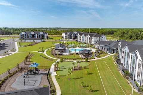 Drone photo of an overview of the property with a playground, pool and golf course.