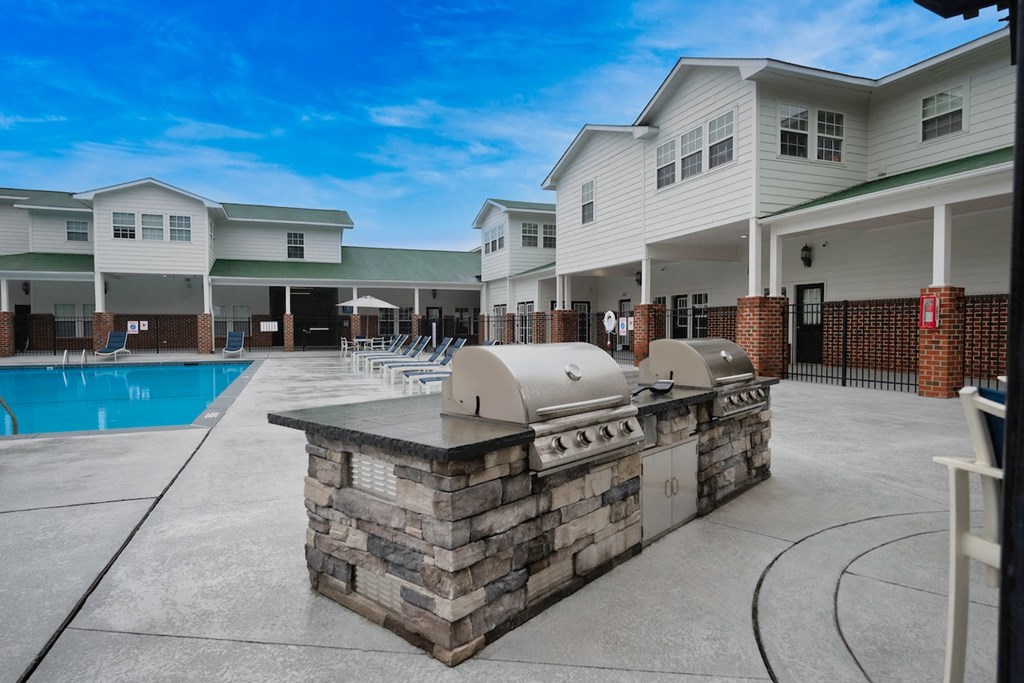 a patio with a grill and a pool in front of a building