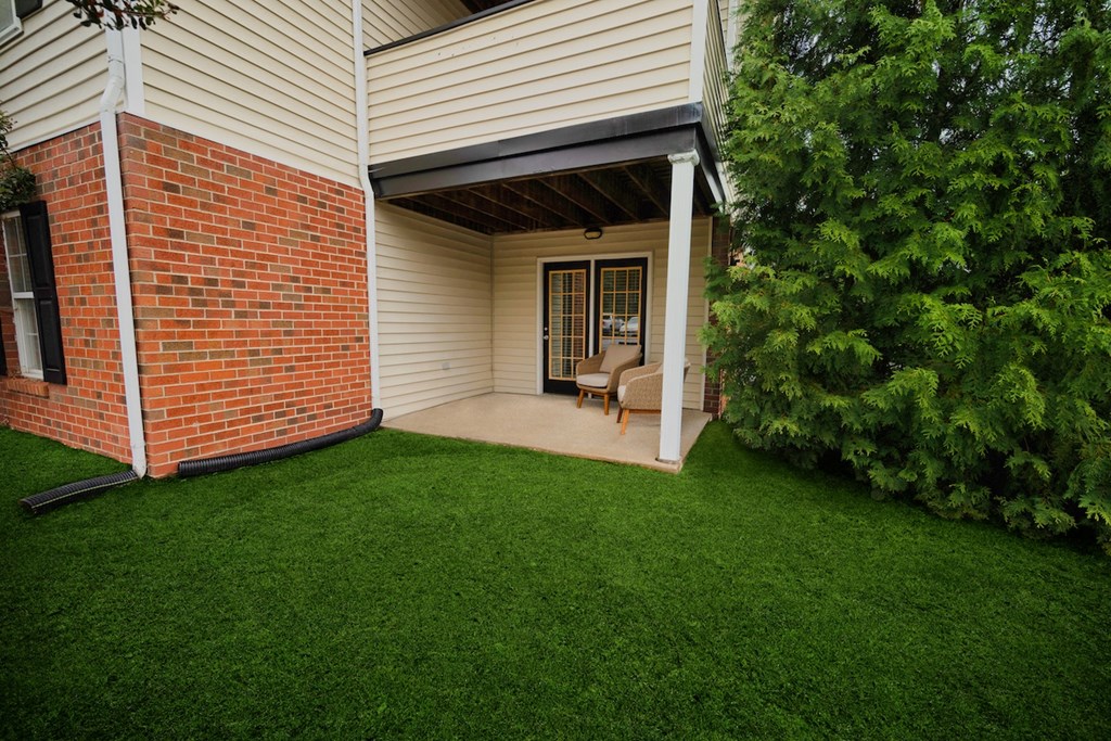 a covered porch with a lawn and a brick house
