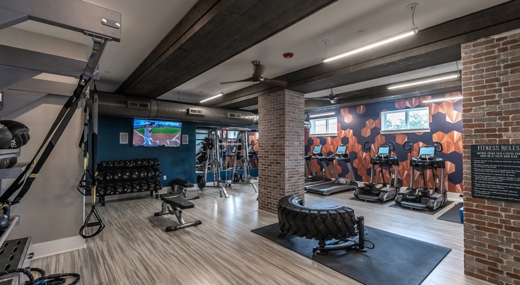 a gym with exercise equipment and a wall mural of a basketball game