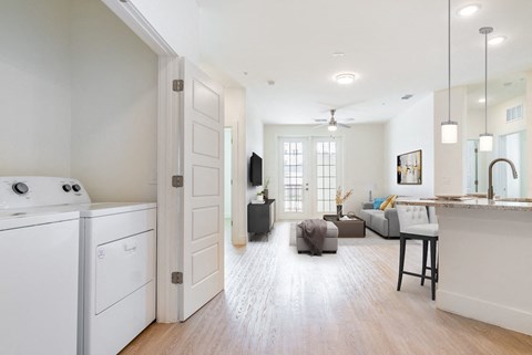 an open kitchen and living room with a washer and dryer