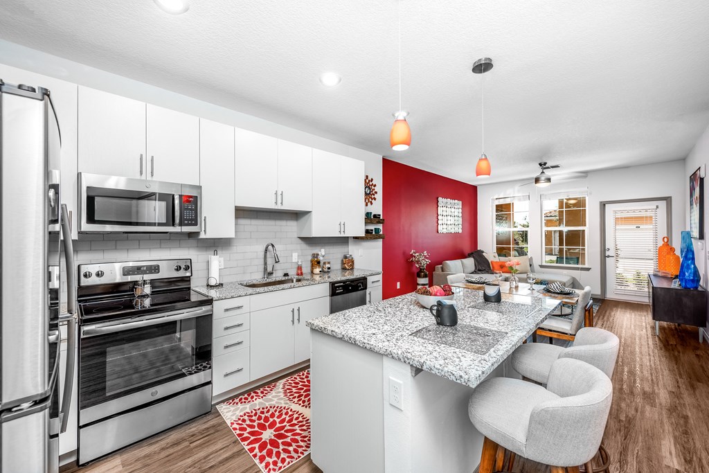 the kitchen and living room of a house with white cabinets and a granite counter top