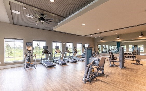 the fitness center has cardio machines and other cardio equipment in a large room with windows