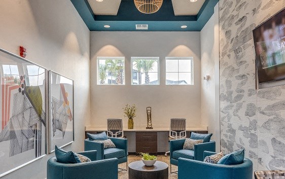 a lobby with blue chairs and a table and a wall with a tv