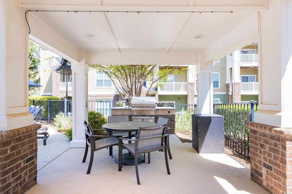 a patio with a table and chairs and a grill