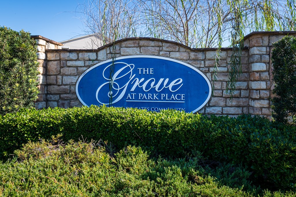a sign for the grove at park place in front of a stone wall