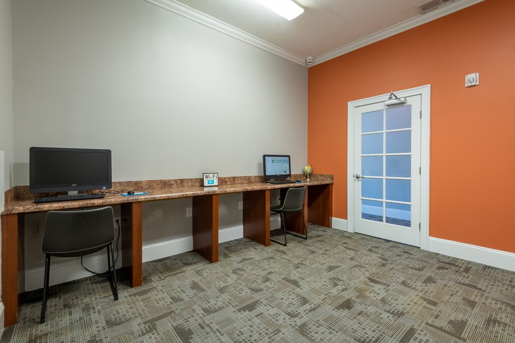 a business center with desks and chairs and a monitor