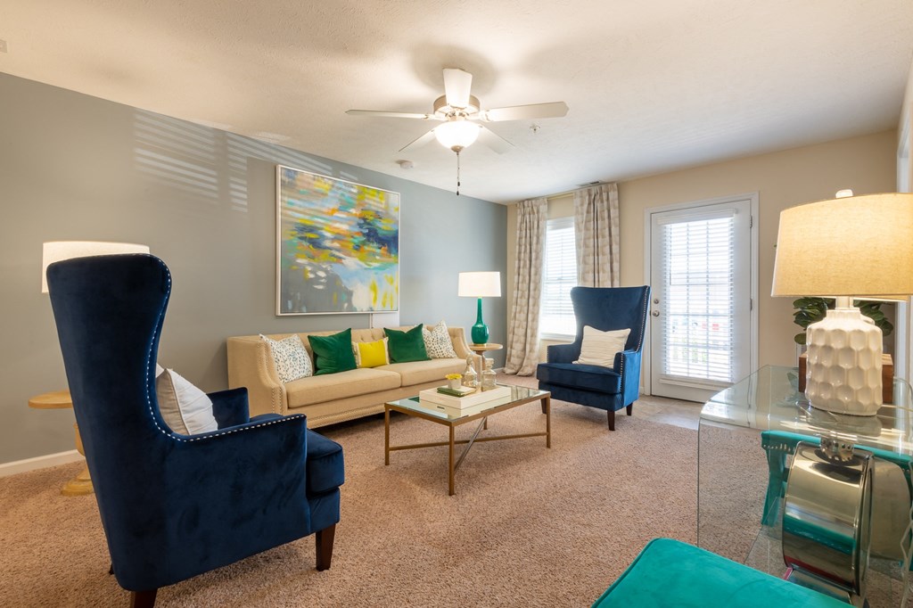 a living room with a couch and chairs and a ceiling fan