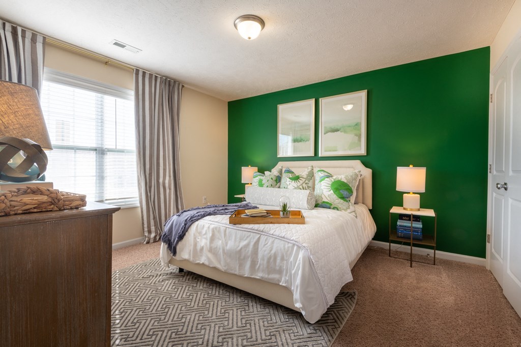 a bedroom with a green wall and a white bed