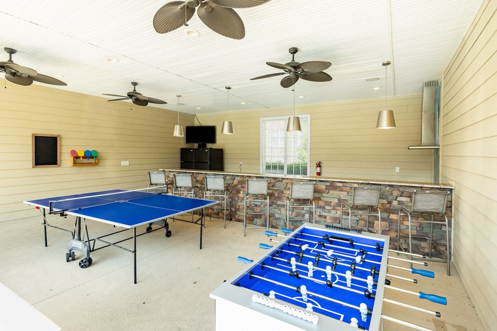 a game room with two ping pong tables and a bar