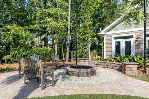 a patio with a fire pit and wooden chairs