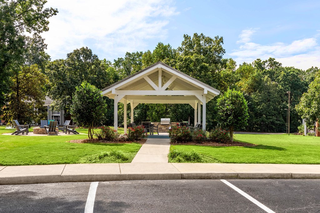 a pavilion with a sidewalk and picnic table in a park