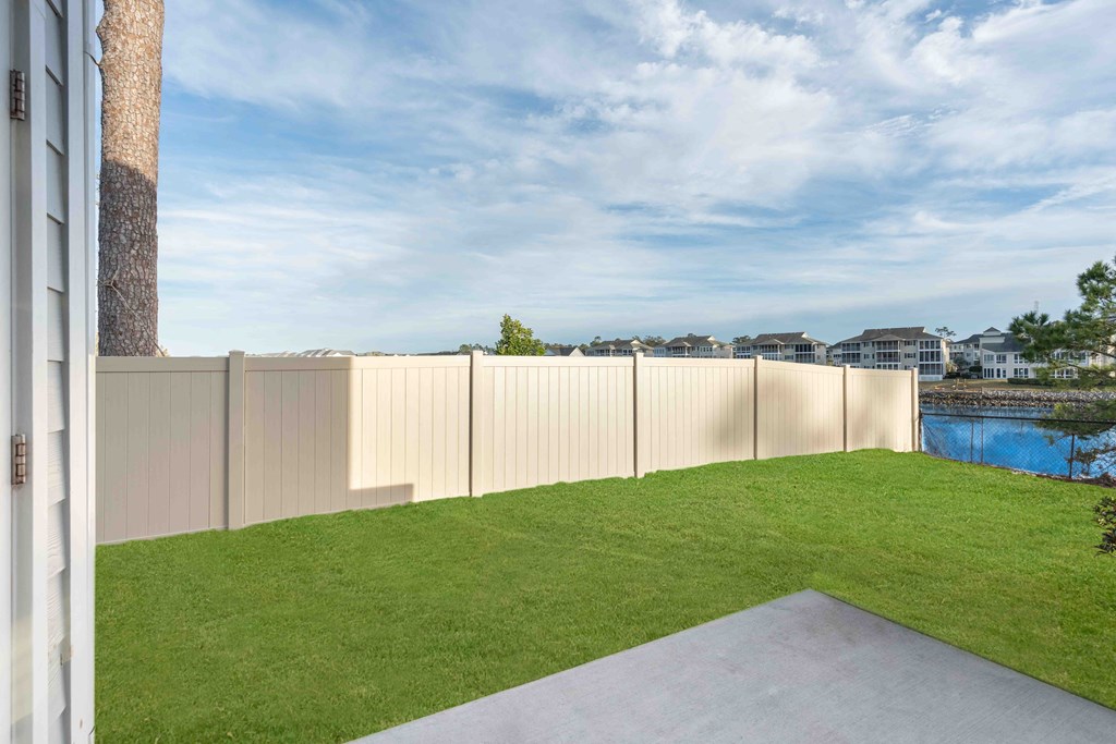 the backyard is fenced in with a pool and grass