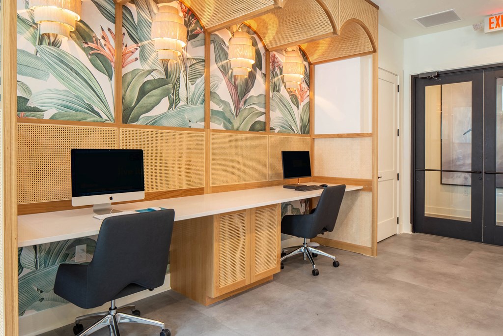 a large desk with two monitors in a room with two chairs
