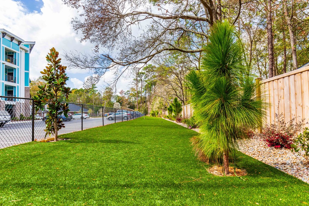 a yard with green grass next to a fence