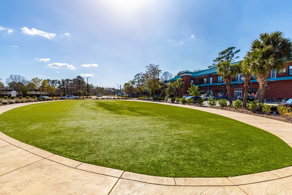 an oval lawn in front of a building with palm trees