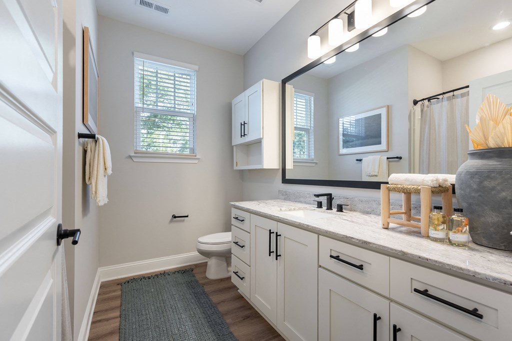 a bathroom with white cabinets and a large mirror and a toilet