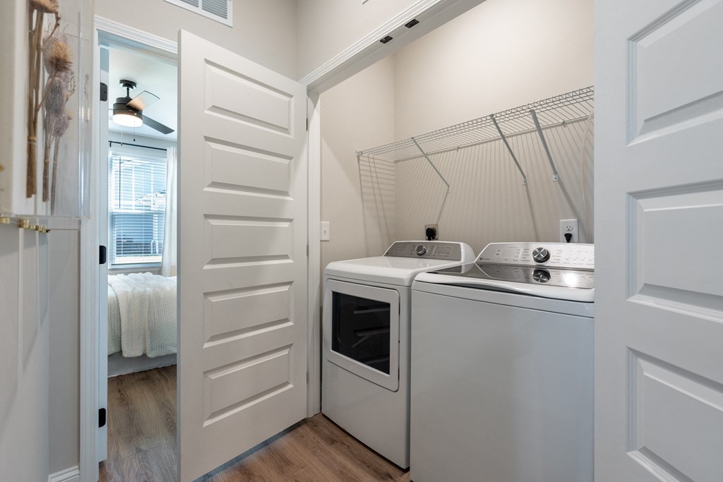 a laundry room with a washer and dryer and a door to a bathroom