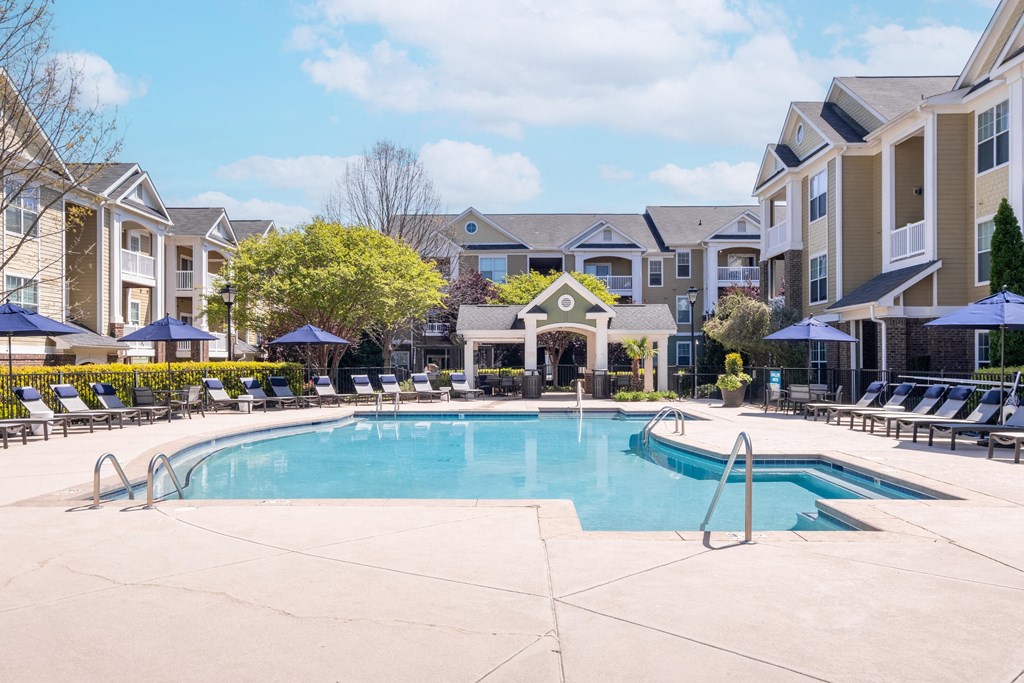 a swimming pool with lounge chairs and umbrellas in front of a building
