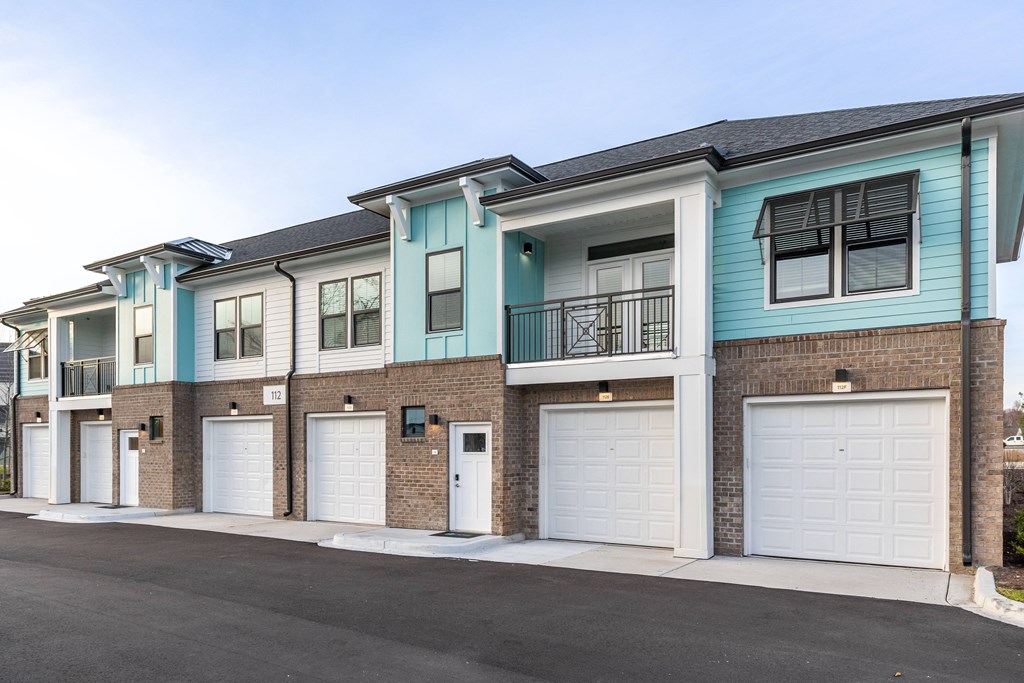 a street view of an apartment building with white garage doors