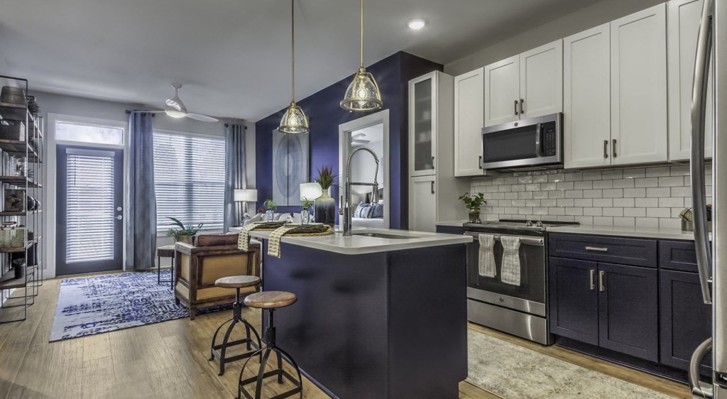 an open kitchen and living room with blue walls and white cabinets